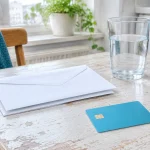 Na kuchynskom stole leží kopa prázdnych obálok a plastová platobná karta bez označenia.